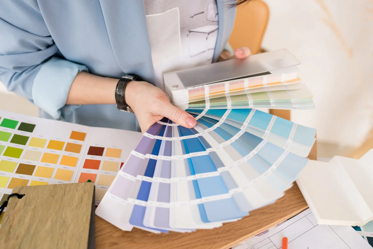 Close-up of architect woman choosing samples of wall paint. Interior designer looking at color swatch for creating project. House renovation, architecture and interior design concept